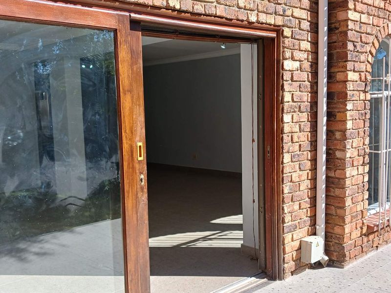 Exterior view of a townhouse featuring exposed brickwork, arched windows with security bars, and a sliding timber door leading into the interior living space.