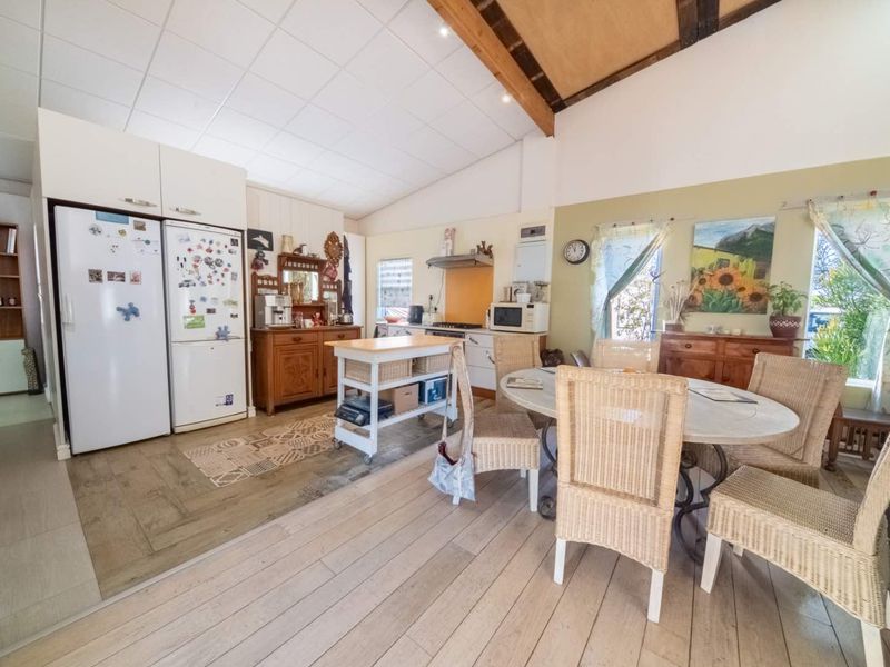 Spacious open-plan kitchen and dining area featuring vaulted ceilings with exposed timber beams and durable laminate flooring.