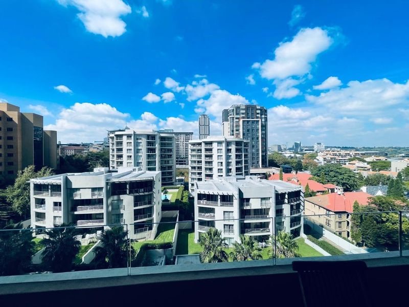Elevated urban view overlooking surrounding apartment complexes and residential neighborhood with a clear glass balustrade in the foreground.