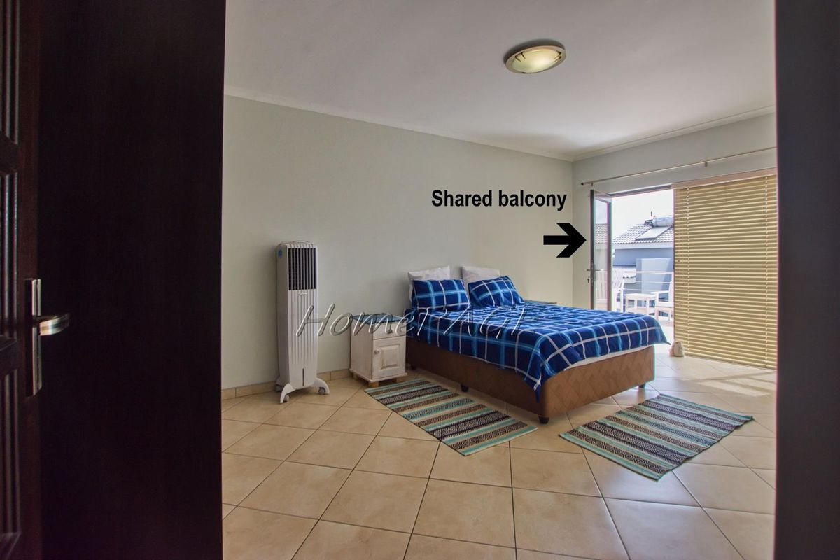 Spacious bedroom featuring tiled flooring and direct access to a shared balcony through glass sliding doors.