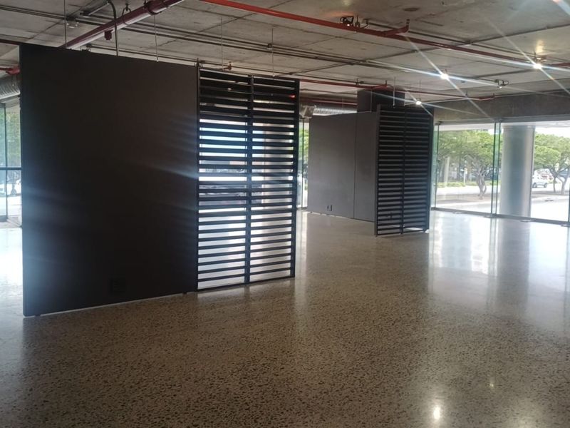 Spacious open-plan retail area featuring polished concrete floors, exposed industrial ceilings, and floor-to-ceiling glass windows with modern decorative metal partitions.