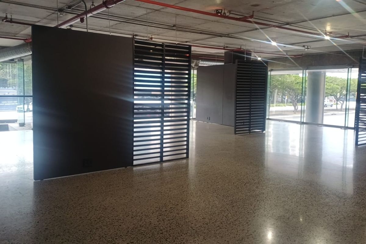Spacious open-plan retail area featuring polished concrete floors, exposed industrial ceilings, and floor-to-ceiling glass windows with modern decorative metal partitions.