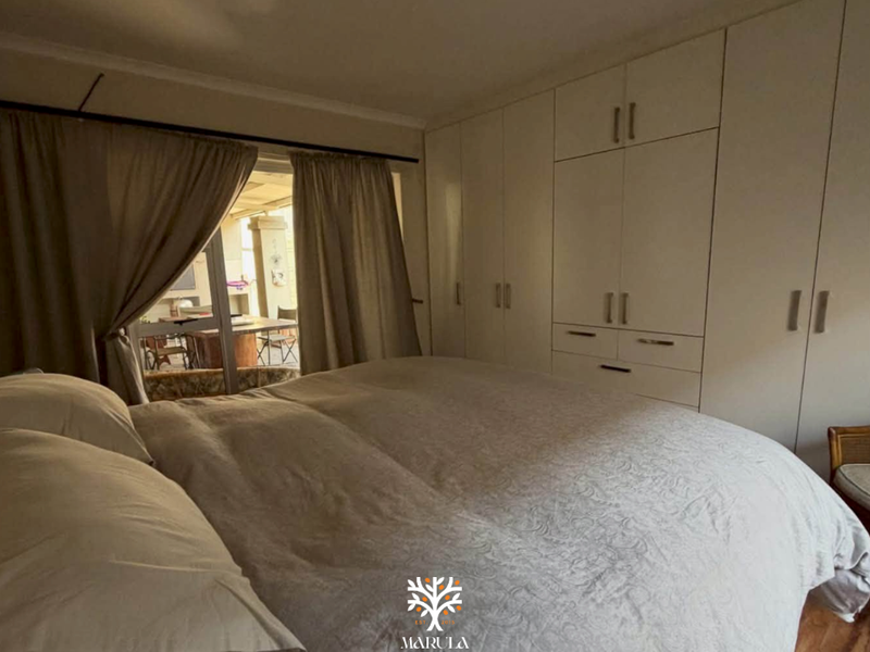 A bedroom featuring extensive built-in cupboards and a sliding door providing access to an outdoor patio area.