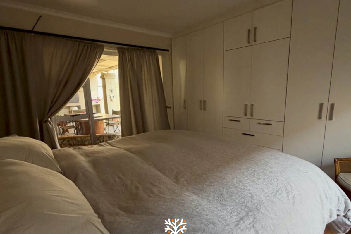 A bedroom featuring extensive built-in cupboards and a sliding door providing access to an outdoor patio area.