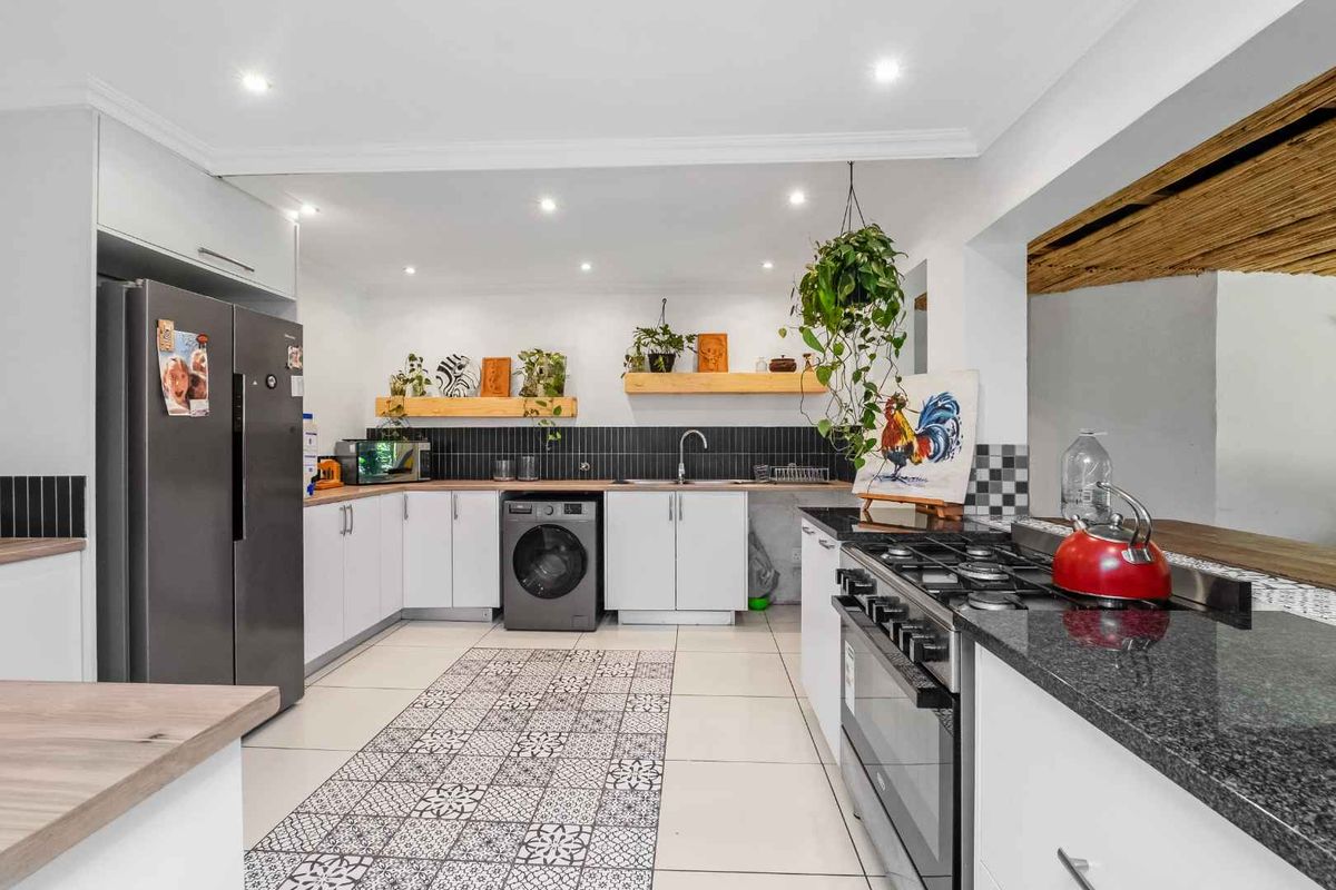 Modern kitchen featuring white cabinetry, dark granite countertops, a gas hob, integrated oven, and stylish tiled flooring with recessed ceiling lighting.