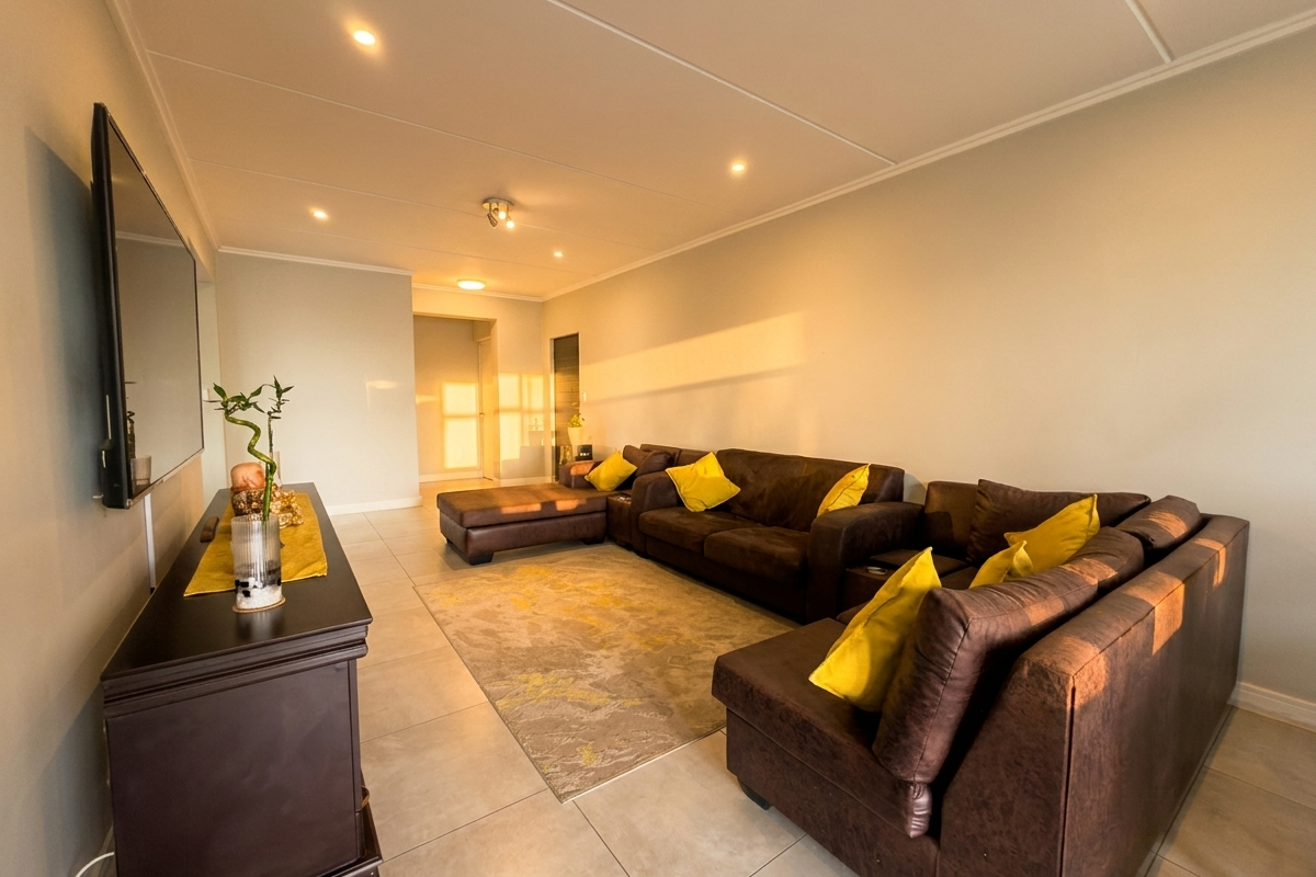 Spacious living room featuring neutral tiled flooring, recessed ceiling lighting, and a wall-mounted television setup.