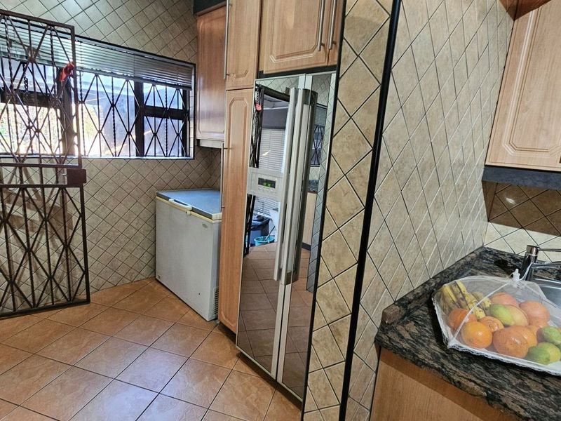 A functional kitchen featuring built-in cabinetry, granite countertops, a stainless steel sink, and tiled finishes throughout.