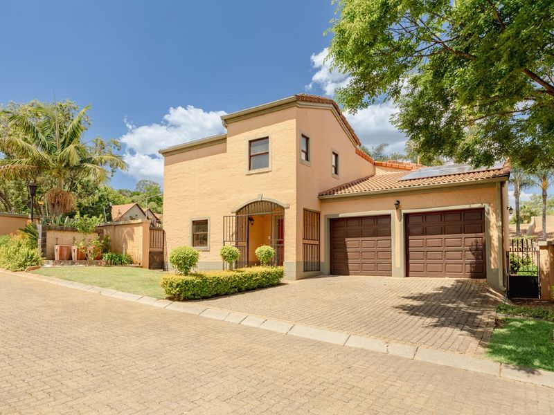 Front view of a double-story residential house featuring a paved driveway, double garage, and well-maintained garden area.