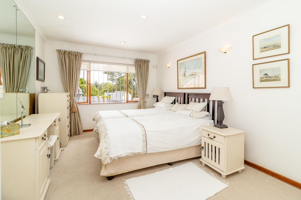 A well-maintained bedroom featuring neutral carpeting, recessed ceiling lighting, and large windows that provide natural light and a view of the surrounding area.