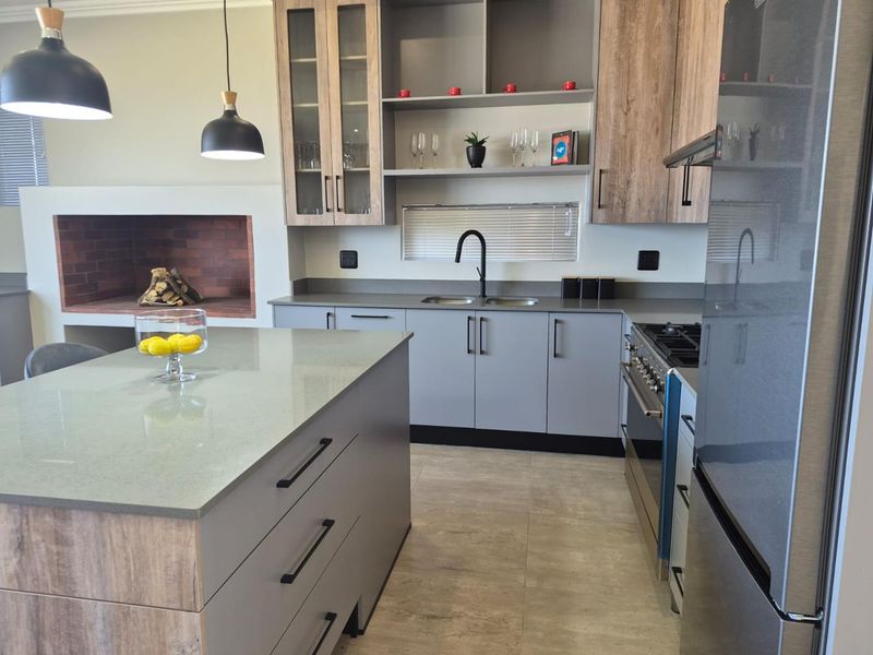 Modern kitchen featuring a central island, quartz countertops, built-in cabinetry, gas hob, and an integrated indoor fireplace for a warm, functional living space.