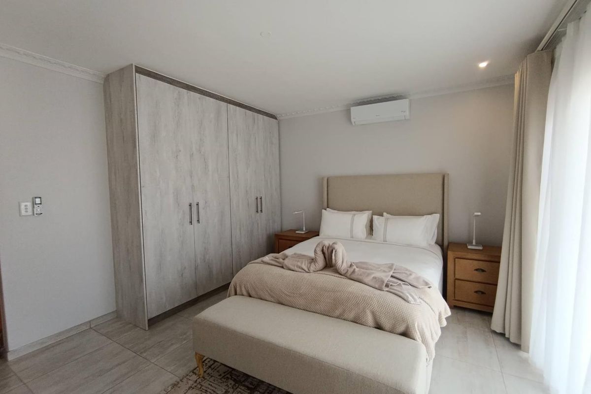 A well-maintained bedroom featuring built-in cabinetry, tiled flooring, and a wall-mounted air conditioning unit.