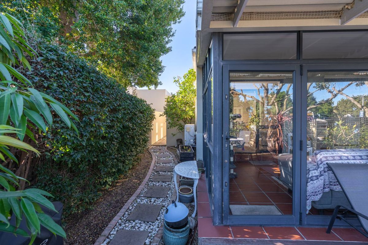 A side garden path featuring stone pavers leading to a rear patio area with aluminium framed glass doors.