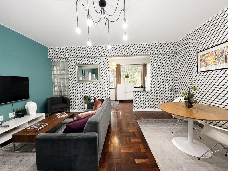 Open plan living and dining area featuring classic parquet flooring, a decorative glass block feature wall, and a convenient pass-through to the kitchen.