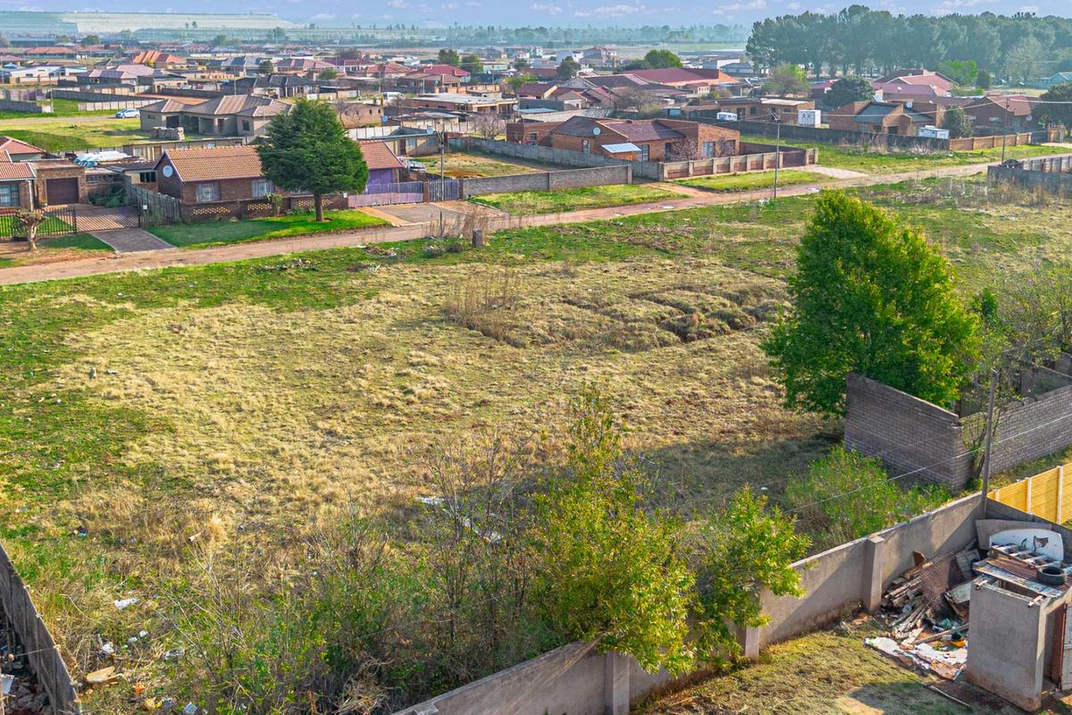 Aerial view of a vacant residential plot featuring perimeter walling and surrounding neighborhood infrastructure.