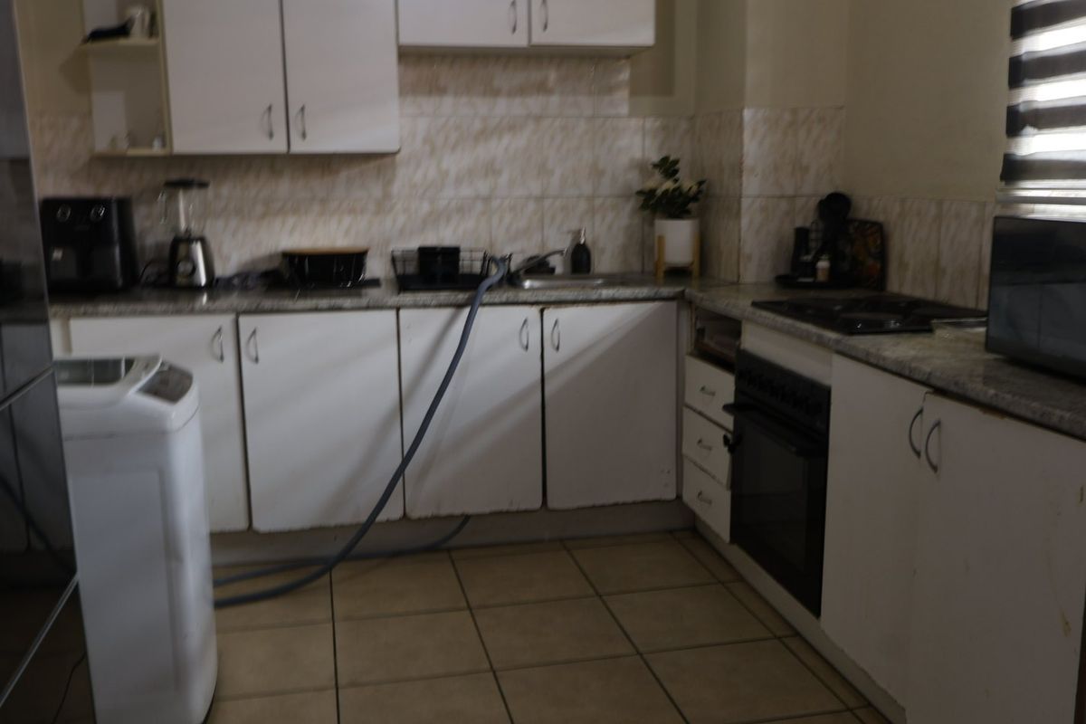 A functional kitchen featuring white cabinetry, stone countertops, tiled backsplash, and built-in oven with hob, requiring cosmetic updates to improve aesthetic appeal.
