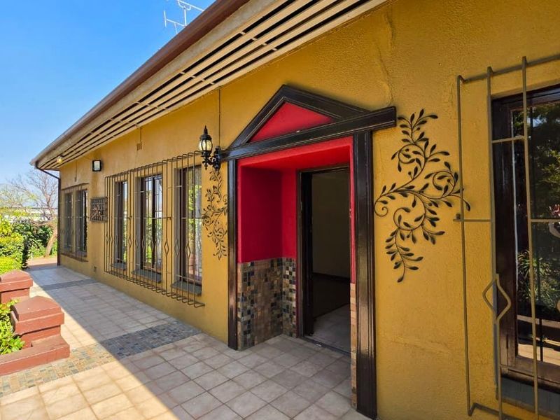 Rear exterior view featuring a tiled patio area, security bars on windows, and a decorative entrance with tiled detailing.