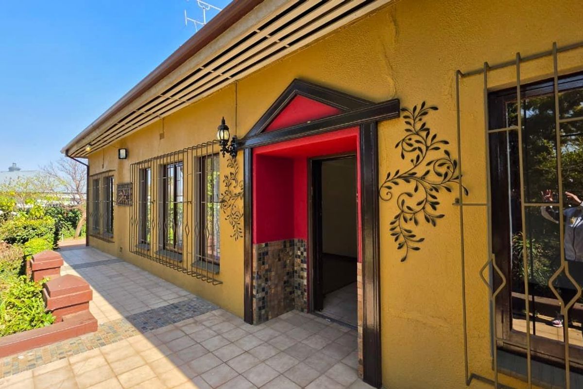 Rear exterior view featuring a tiled patio area, security bars on windows, and a decorative entrance with tiled detailing.