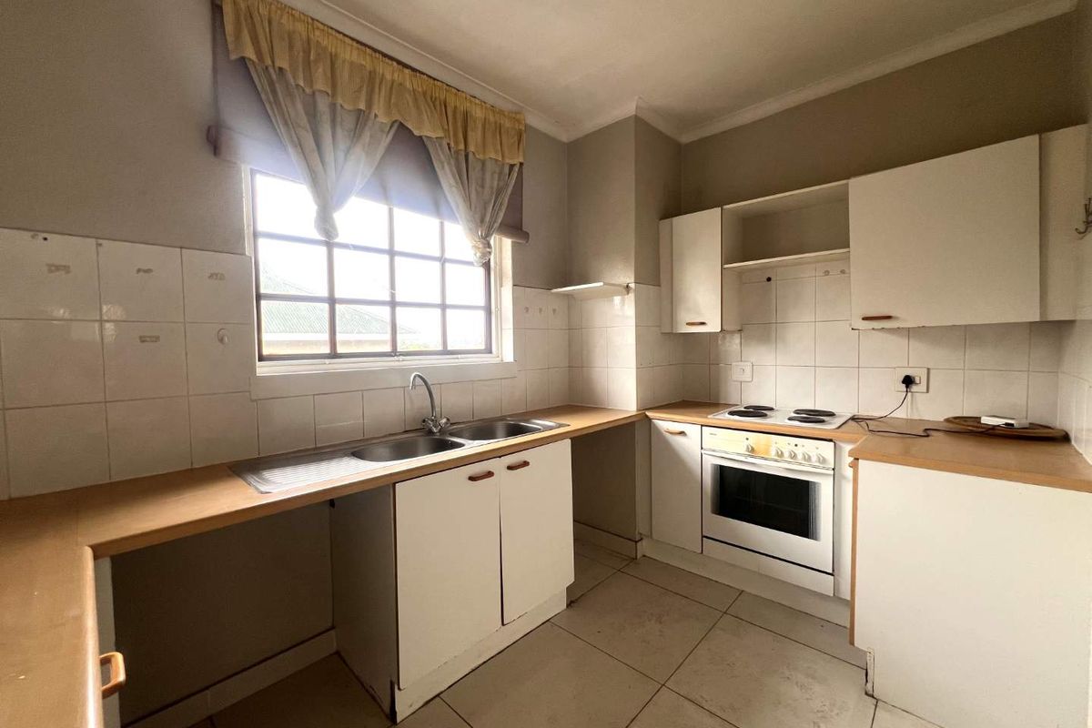 A functional kitchen featuring built-in cabinetry, laminate countertops, a double basin sink, and an integrated electric oven and hob with tiled splashbacks.
