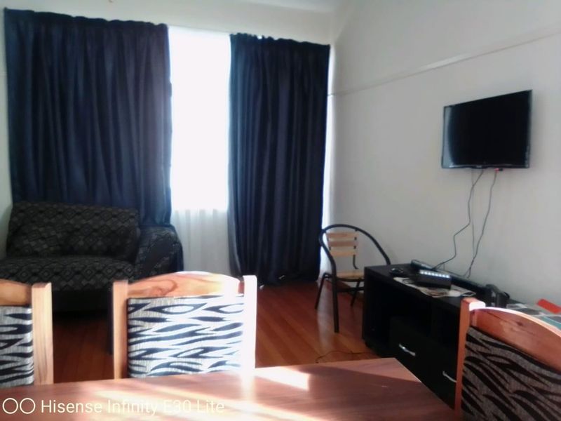 A living room area featuring hardwood flooring and window curtains.