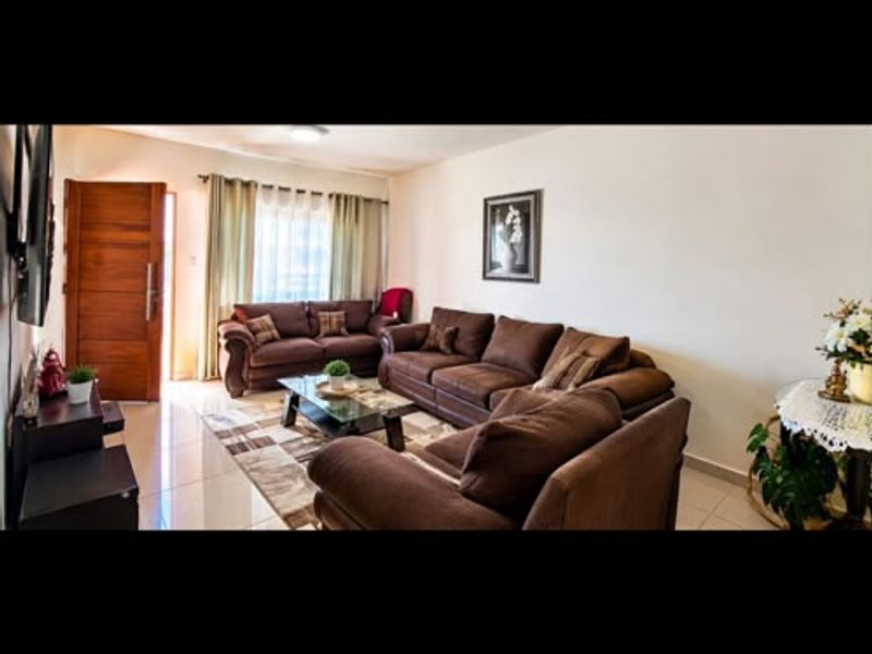 A comfortable living room featuring tiled flooring and a wooden entrance door, providing a functional and welcoming space for relaxation.