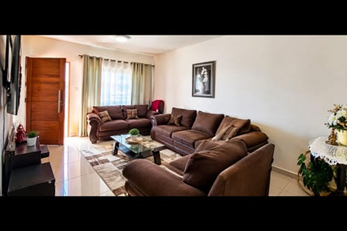 A comfortable living room featuring tiled flooring and a wooden entrance door, providing a functional and welcoming space for relaxation.