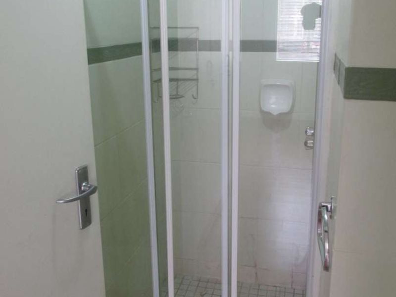 A functional bathroom featuring a tiled shower enclosure with a sliding glass door and wall-mounted shower head.