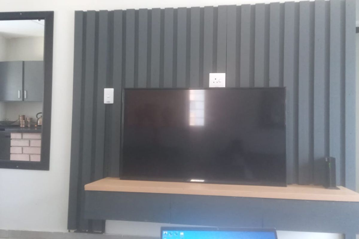 A living room featuring a modern slatted feature wall with a built-in floating media console and integrated electrical points.
