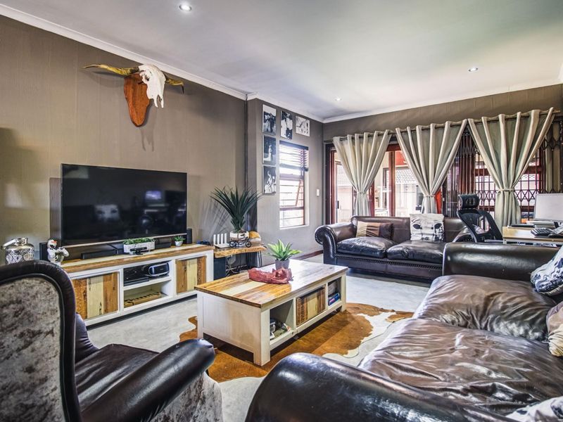 Spacious living room featuring recessed downlights, louver windows, and sliding glass doors leading to an outdoor area, providing a comfortable and functional living space.