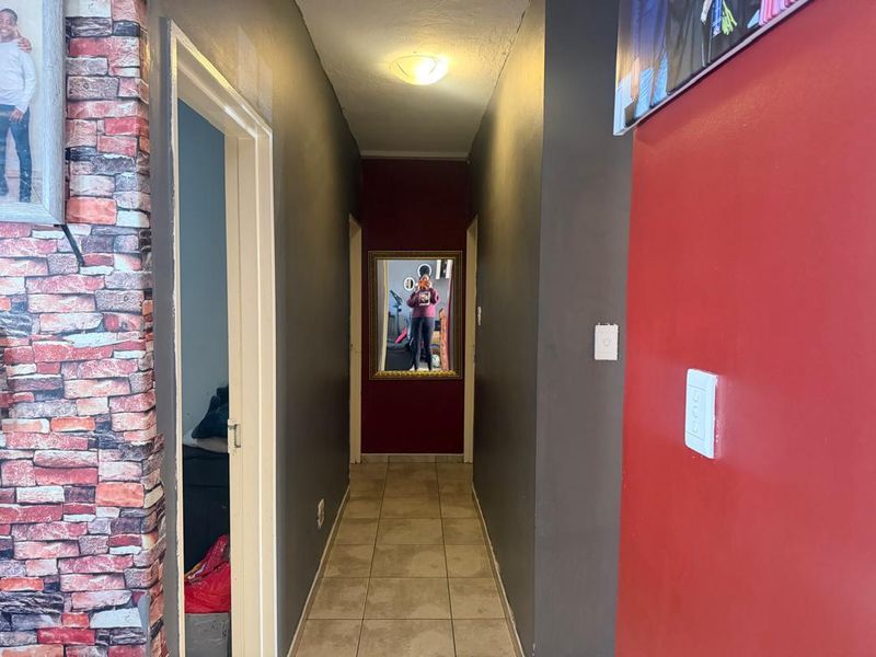 A functional hallway featuring tiled flooring and neutral lighting, connecting various rooms within the apartment.