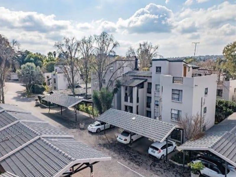 Aerial view of an apartment complex featuring multiple covered parking carports and paved driveway access.