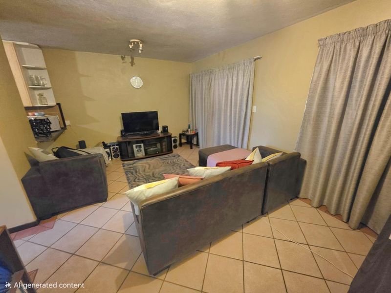 A living room area featuring ceramic floor tiles, a sliding glass door, and built-in shelving, currently showing signs of wear.