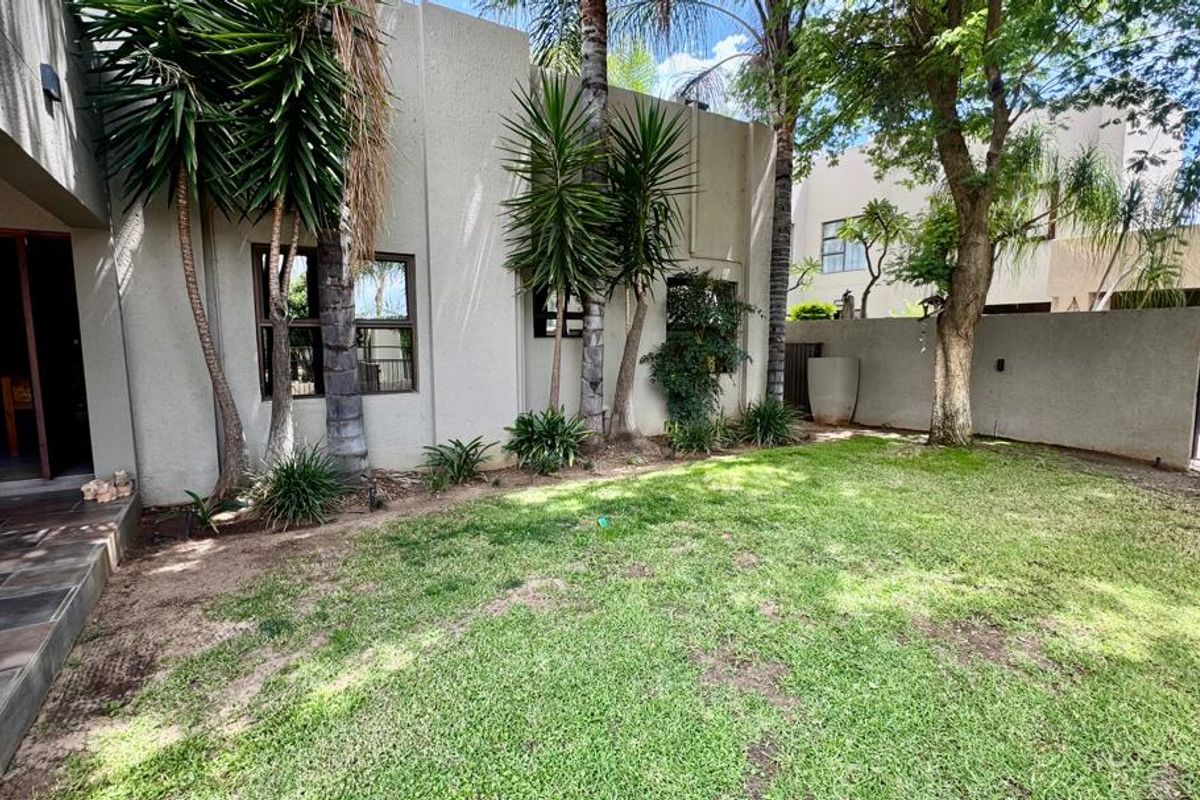 A private rear garden area featuring a lawn, mature trees, and direct access to the home's interior living space.