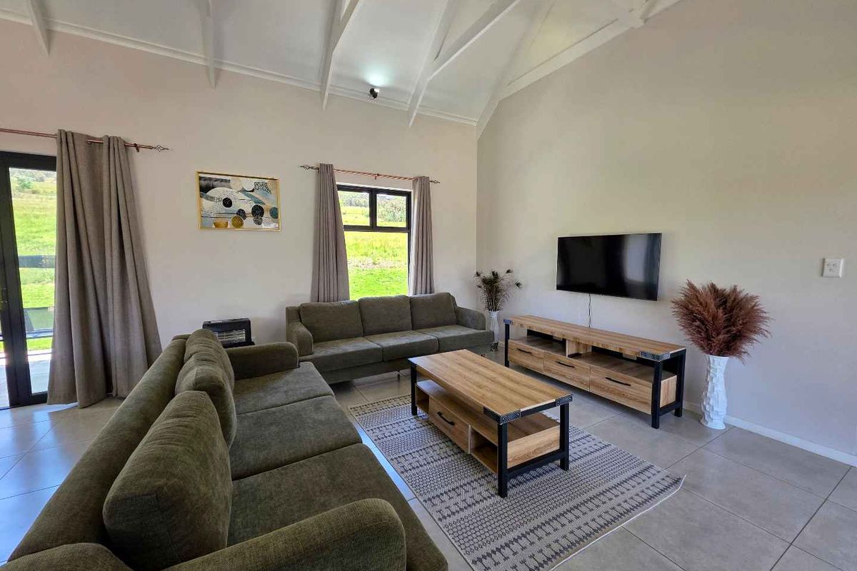 Spacious living room featuring high vaulted ceilings, tiled flooring, and large windows providing natural light and scenic views.