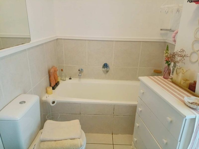 A functional bathroom featuring a built-in bathtub, ceramic tiling, and a standard toilet, offering a clean and practical layout.