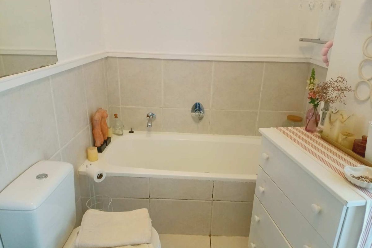 A functional bathroom featuring a built-in bathtub, ceramic tiling, and a standard toilet, offering a clean and practical layout.