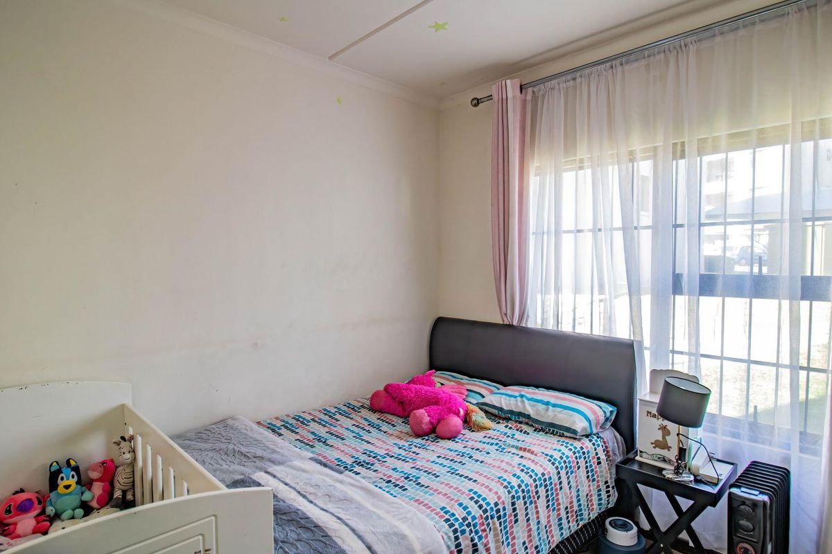 A standard bedroom featuring a large window with curtain rod, providing natural light and a neutral backdrop for potential interior design updates.