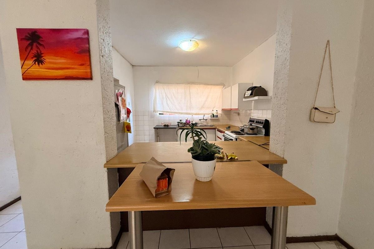 A functional kitchen featuring built-in cabinetry, a tiled backsplash, and a breakfast counter, offering a practical layout with potential for modern updates.