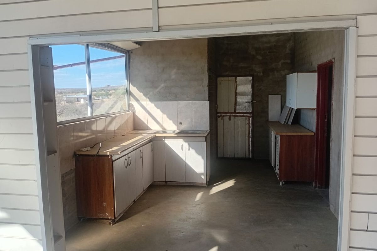 A rustic kitchen area featuring built-in cabinetry, tiled backsplash, and a stable door, requiring cosmetic updates to improve the overall finish.