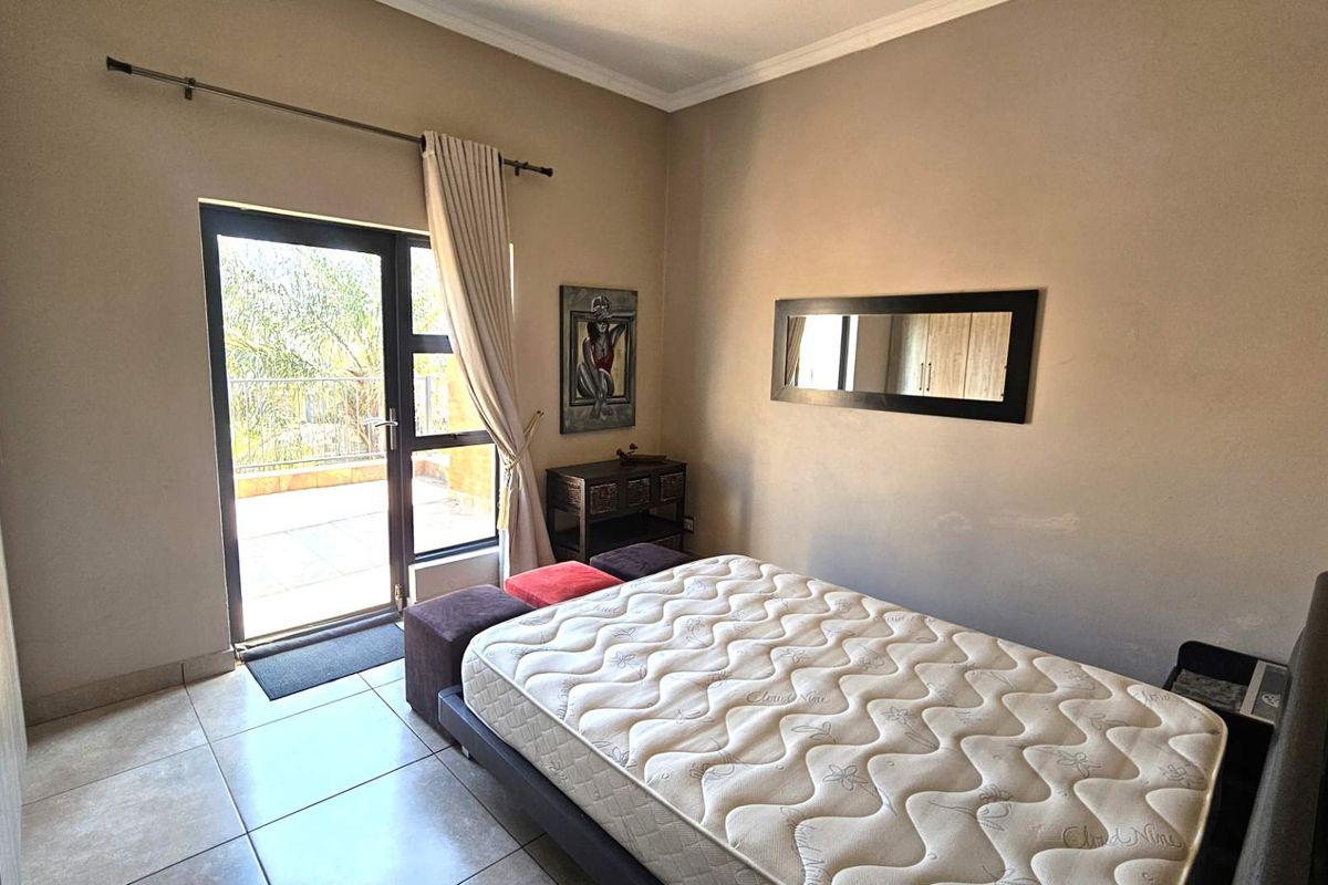 A bedroom featuring tiled flooring, built-in cupboards, and a sliding glass door providing direct access to an outdoor patio area.