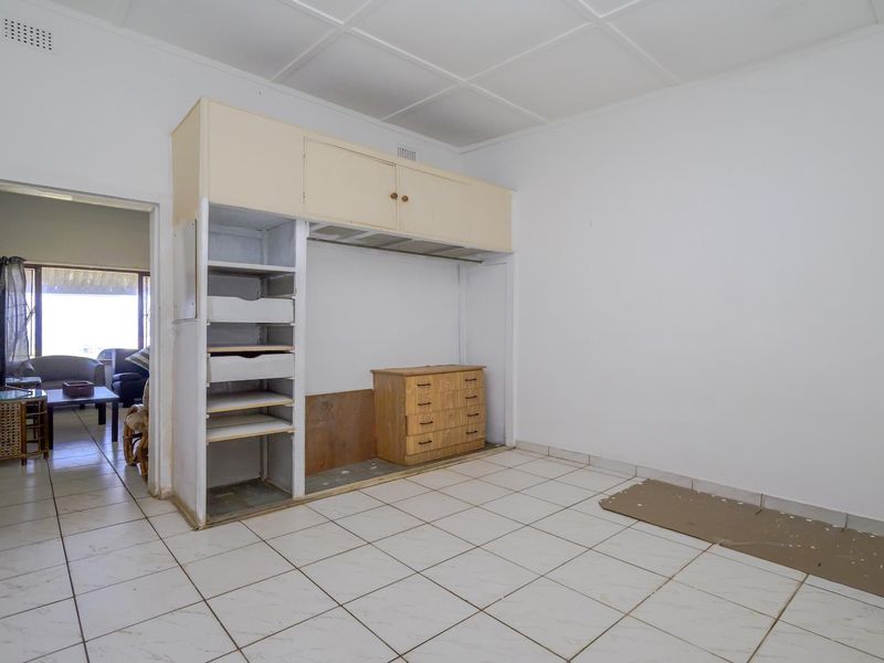 A vacant bedroom featuring tiled flooring and built-in storage cupboards with overhead cabinetry.