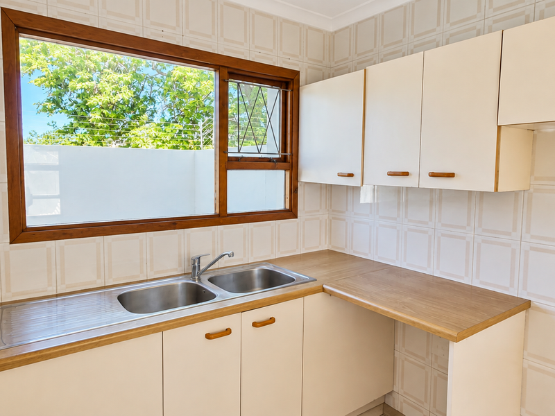 A functional scullery area featuring a double stainless steel sink, laminate countertops, and ample built-in cabinetry with tiled wall finishes.