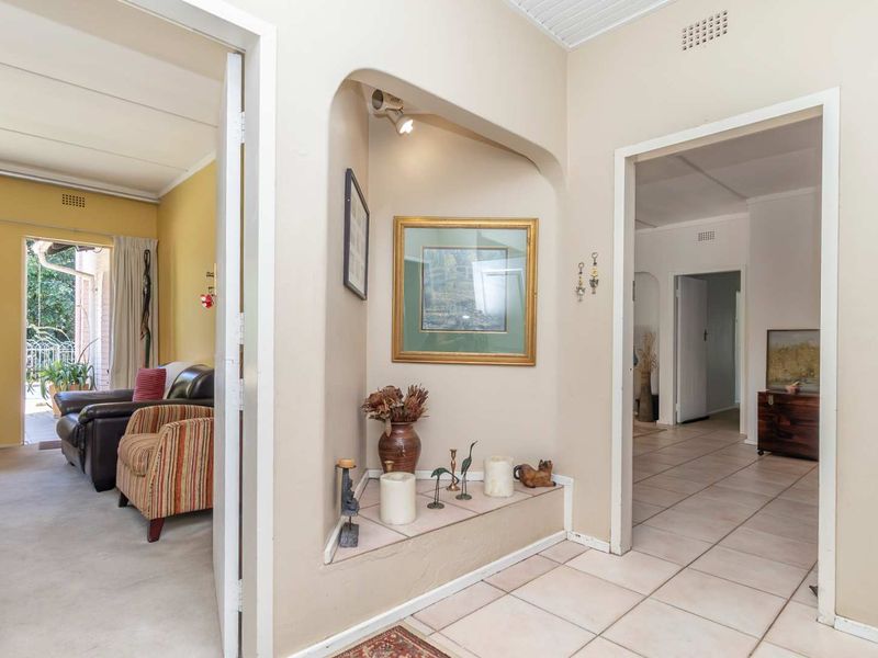 A bright entrance hallway featuring tiled flooring and a unique arched display niche, providing access to adjacent living areas.