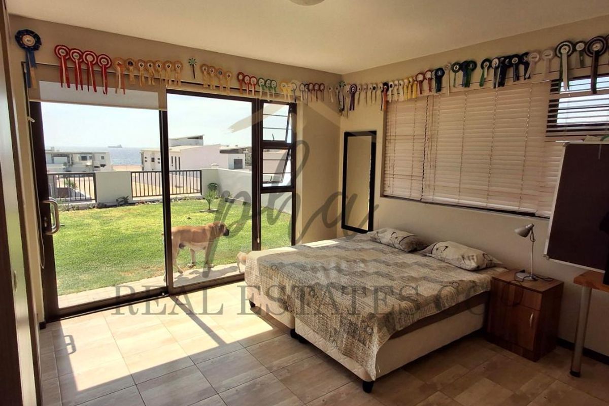 A bedroom featuring tiled flooring and large sliding glass doors that provide direct access to a rear garden and patio area.