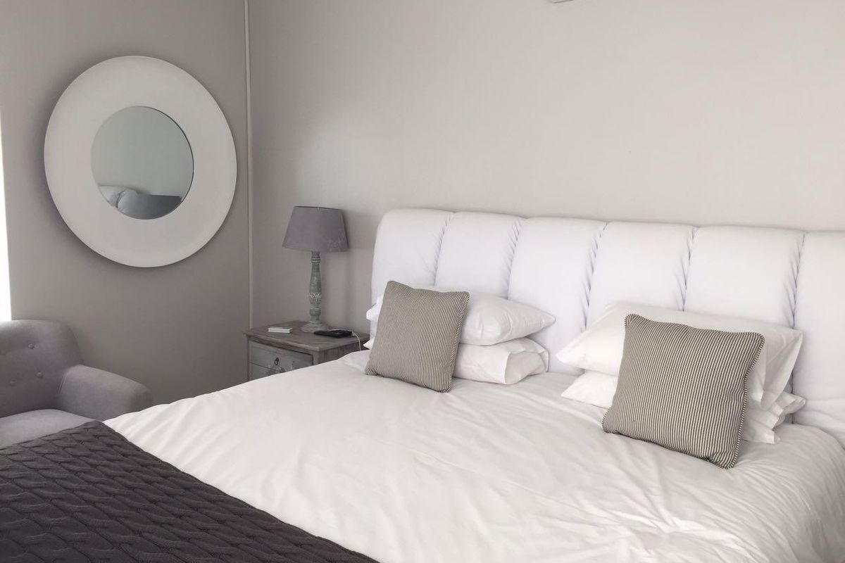 A well-maintained bedroom featuring a wall-mounted air conditioning unit and neutral finishes.