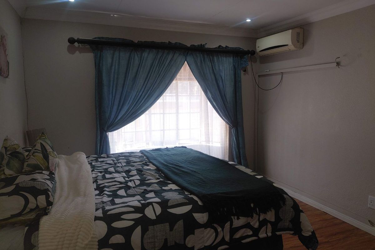 A bedroom featuring laminate flooring, recessed downlighting, and a wall-mounted split-system air conditioner unit.