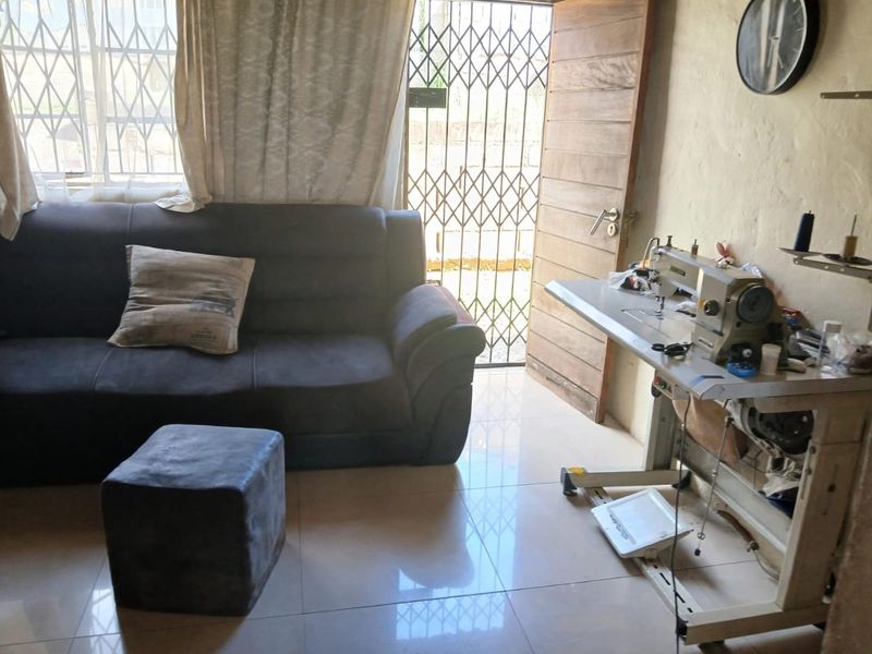 A living area featuring tiled flooring, a security gate, and a timber door, currently utilized as a multi-purpose space.