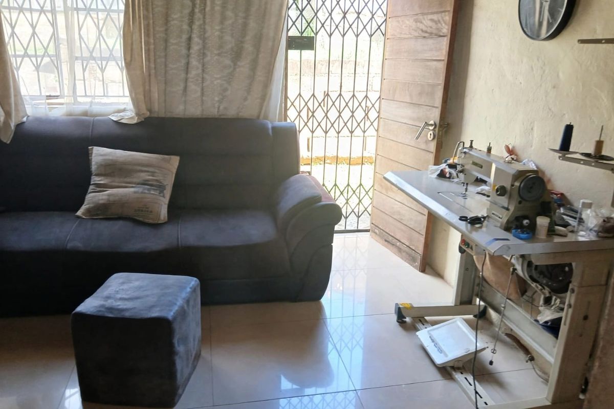 A living area featuring tiled flooring, a security gate, and a timber door, currently utilized as a multi-purpose space.