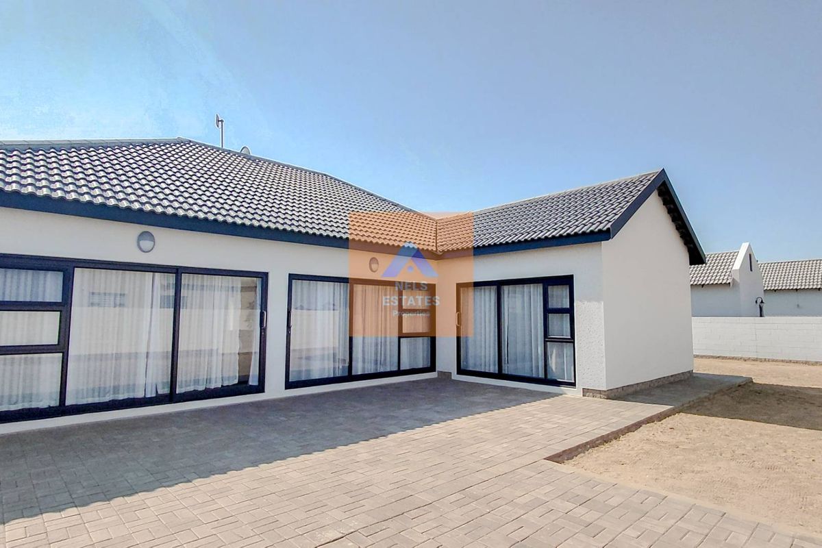 Rear view of the property featuring a paved patio area, modern sliding glass doors, and a well-maintained tiled roof.