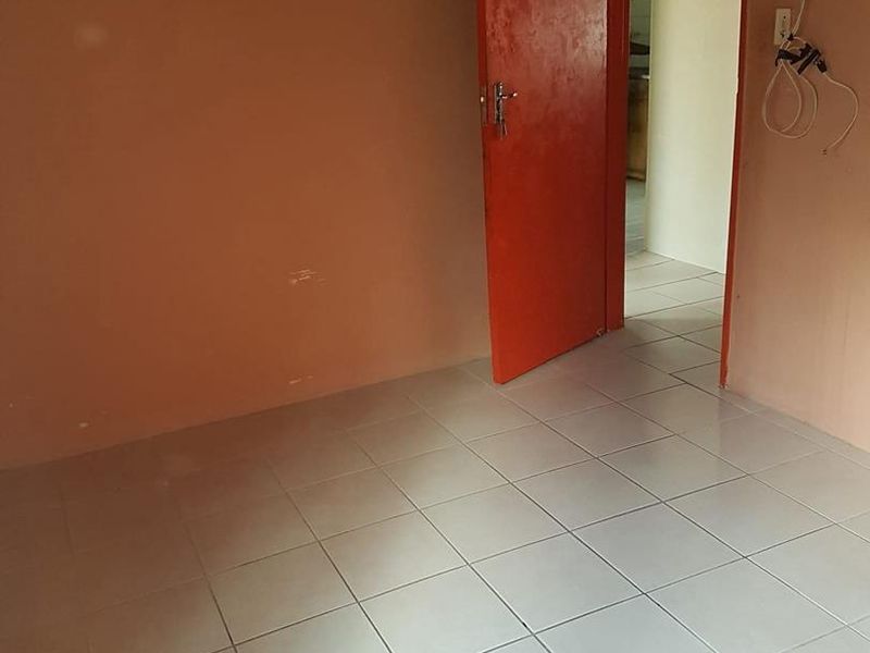 An empty bedroom featuring ceramic floor tiles and an internal door, requiring cosmetic updates and electrical repairs.