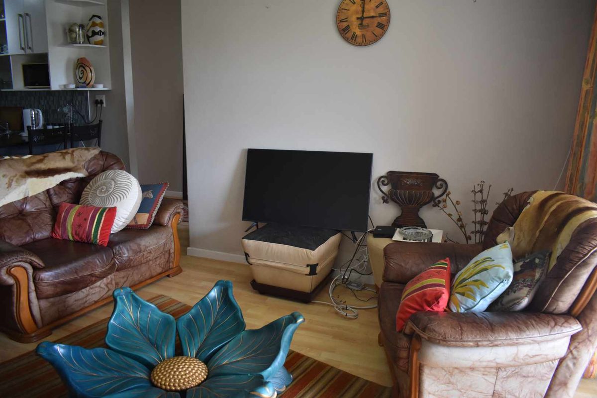 A view of a living room area featuring light wood-look flooring and an adjacent kitchen nook with built-in shelving.